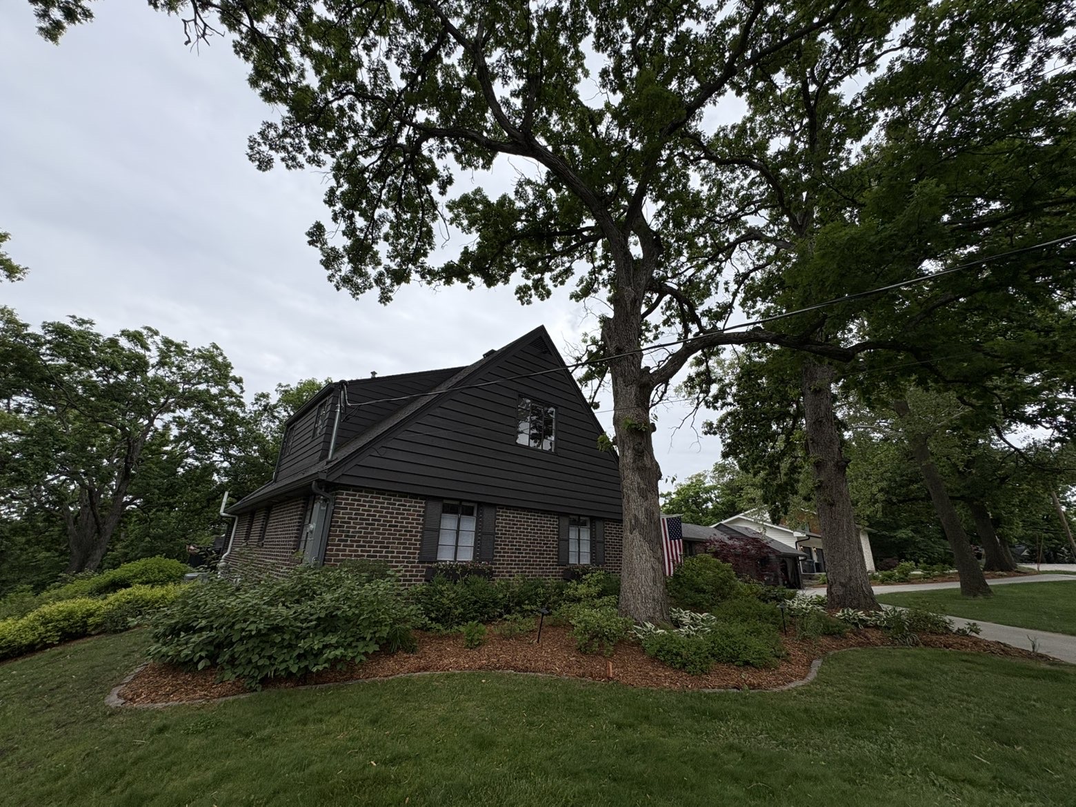 Mature tree landscaping with mulch bed and foundation plantings at Des Moines Iowa home