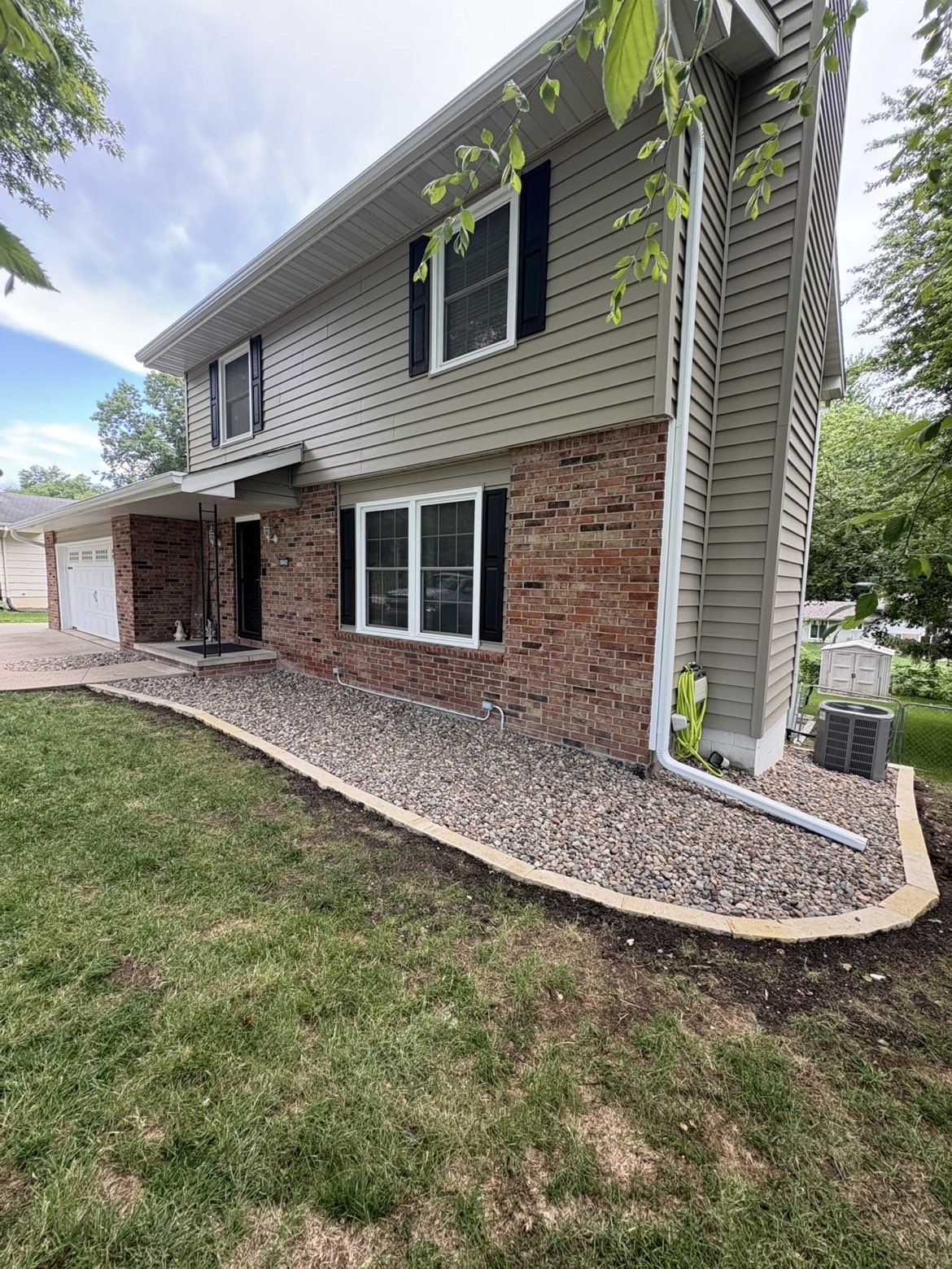 Foundation rock bed landscaping with stone border at brick home exterior in Des Moines Iowa