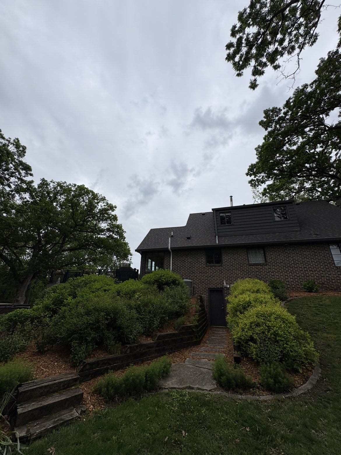 Hillside landscape maintenance with retaining wall and shaped shrubs in Des Moines Iowa