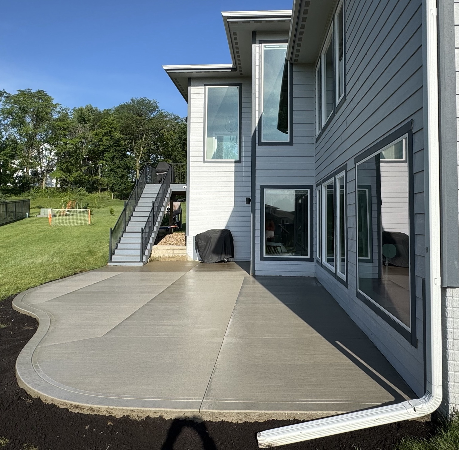 Curved concrete patio with custom cuts behind home