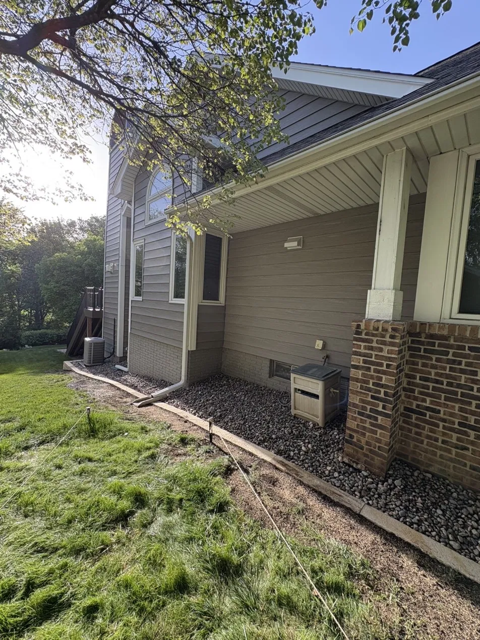 Side yard landscape curbing with gravel drainage bed and stone edging in Des Moines Iowa