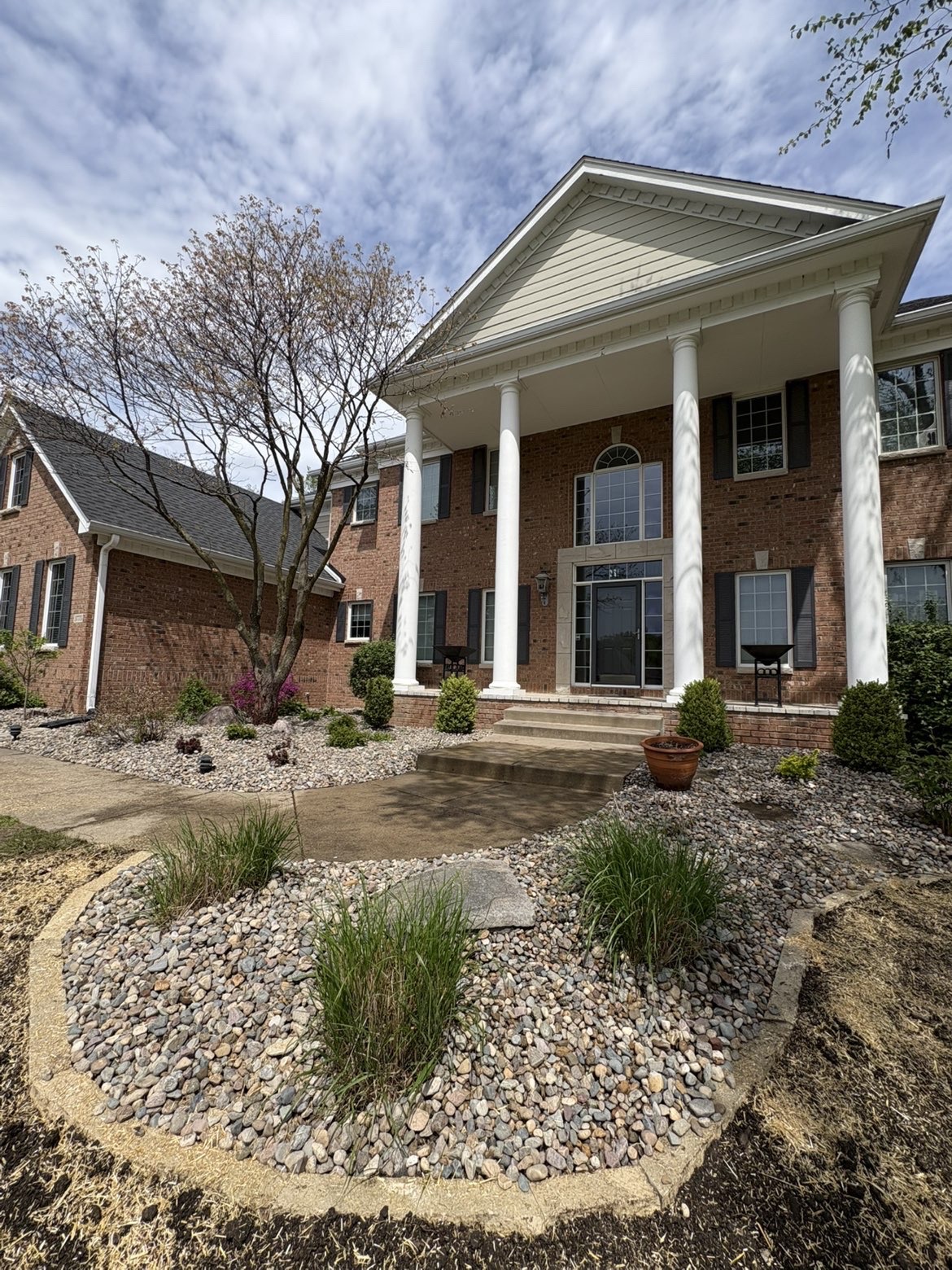 Front yard landscape design with river rock beds and concrete edging in Des Moines Iowa