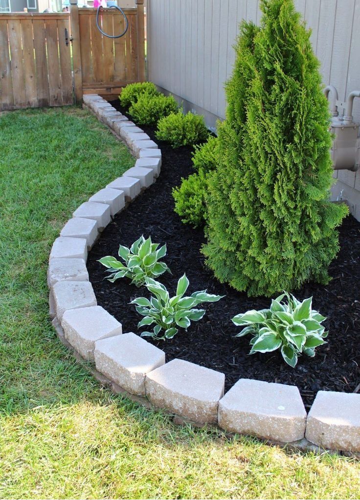 Curved stone edging with evergreens and hostas in backyard bed