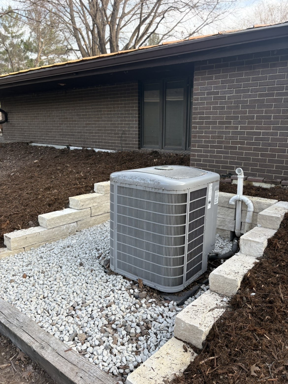 Stone border with white rock around HVAC unit in Des Moines