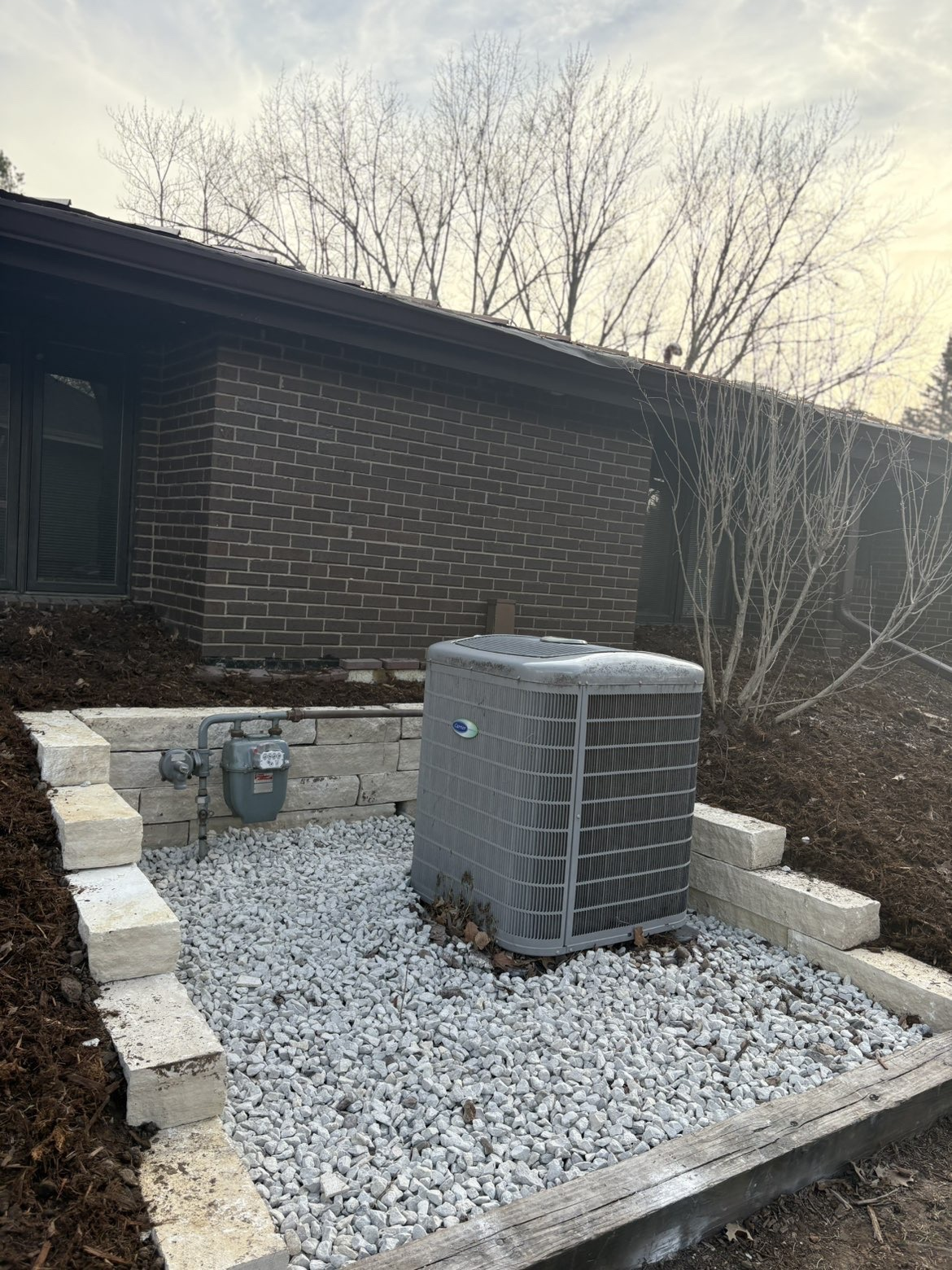 Stone retaining wall with gravel pad around utility equipment in Des Moines