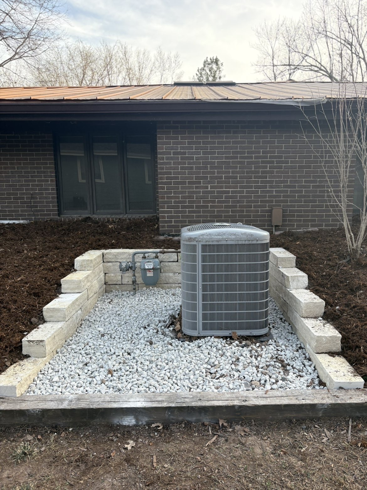 Stone retaining wall border framing HVAC unit in Des Moines