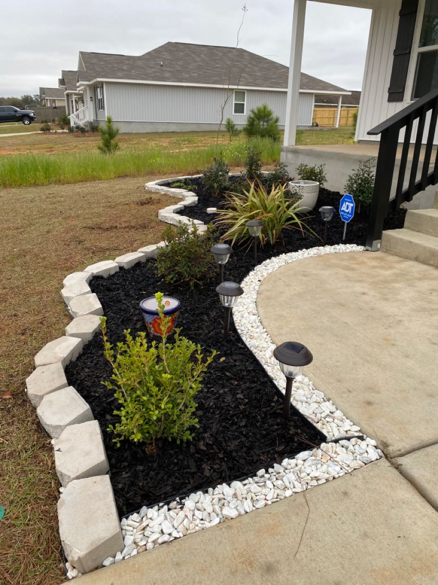 Black mulch with white rock accent and stone border at front entry