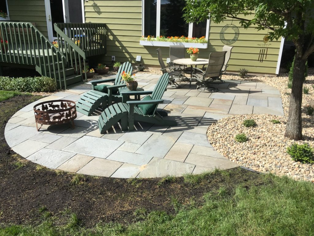 Natural stone patio with Adirondack chairs and fire pit area in Des Moines