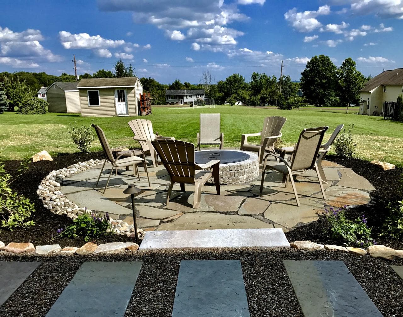 Flagstone fire pit patio with seating area and landscaping in Des Moines