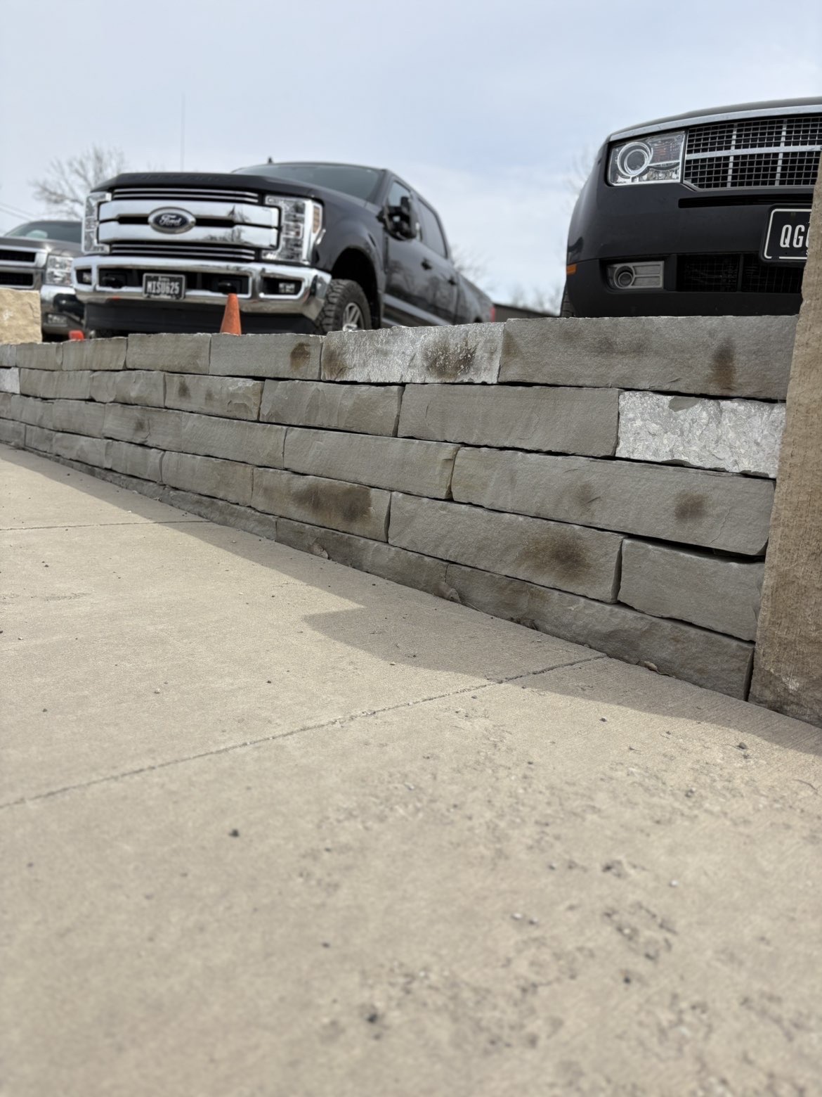 Dark grey stone retaining wall with concrete cap