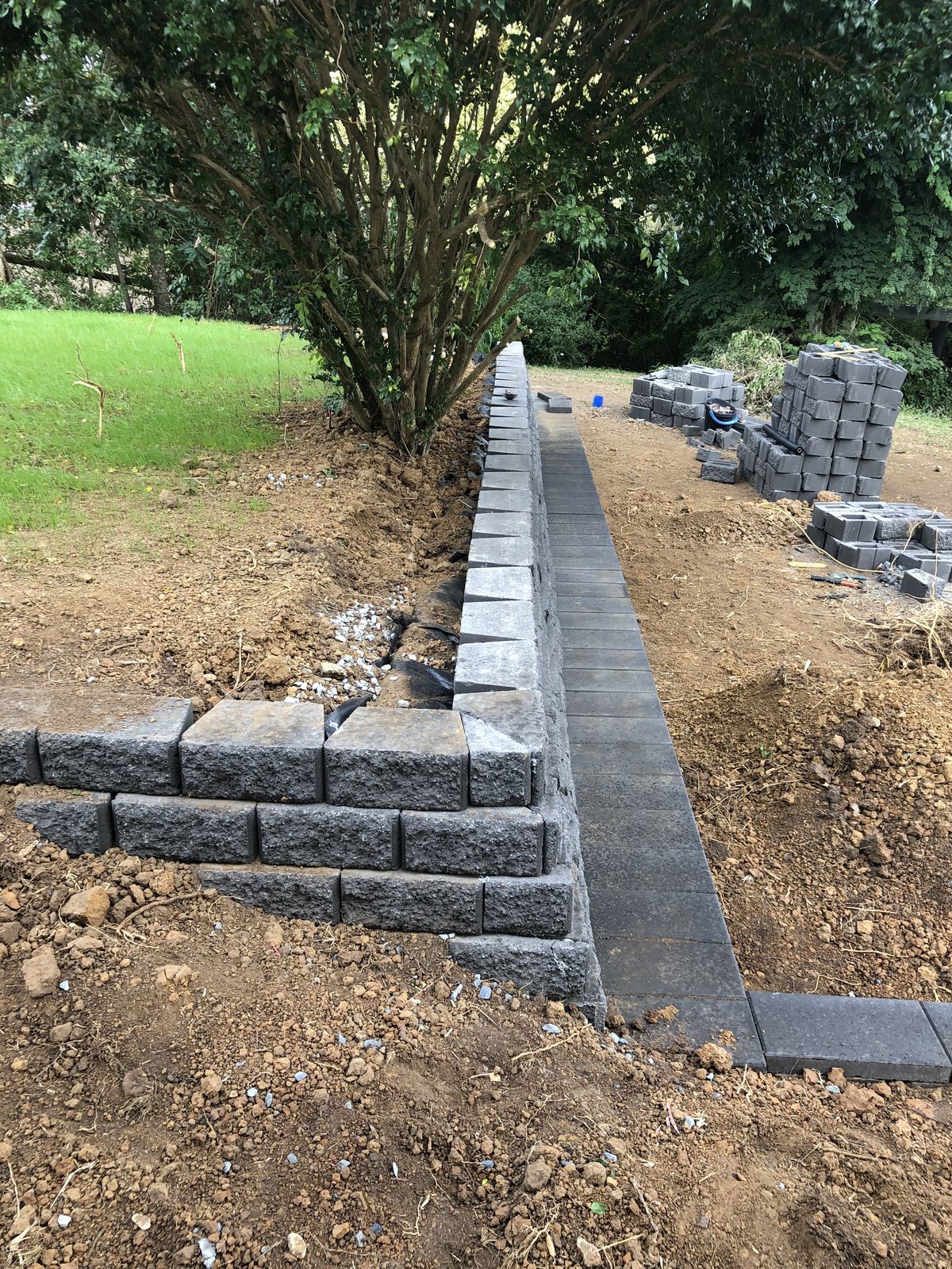 Block retaining wall under construction with drainage gravel in Des Moines