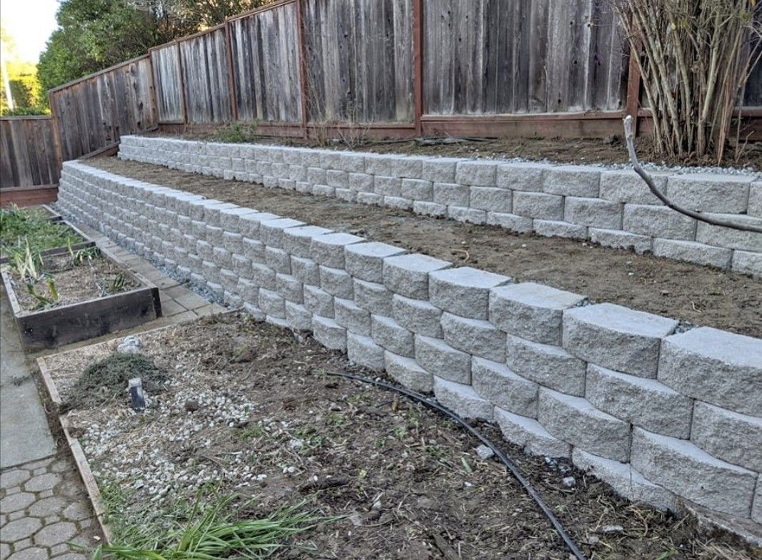 Grey block retaining wall along backyard fence line