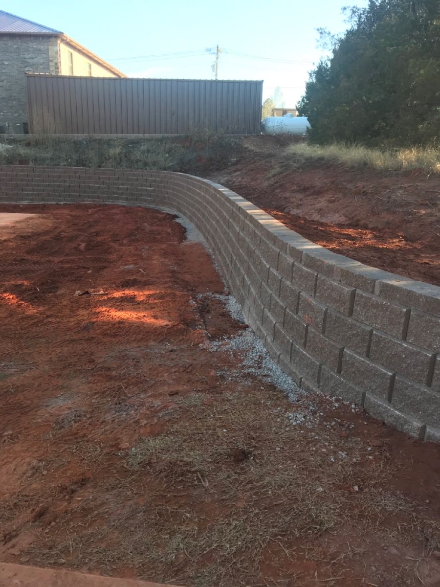 Tall curved retaining wall with drainage gravel on slope